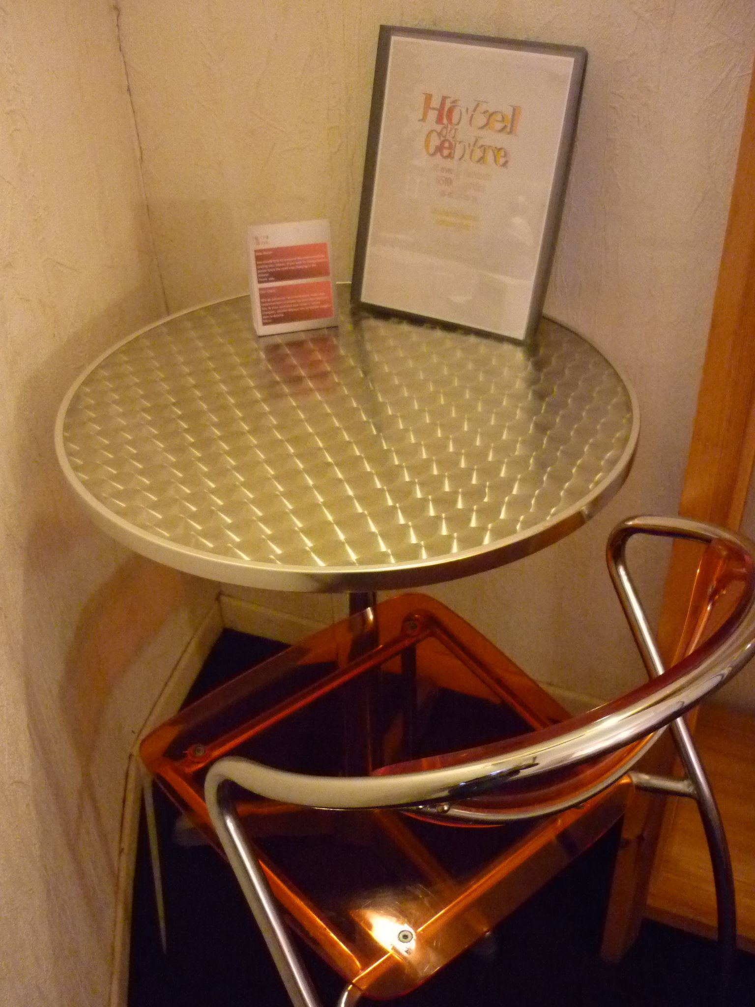 A small round table with a metal top and a single chair with a curved backrest.
