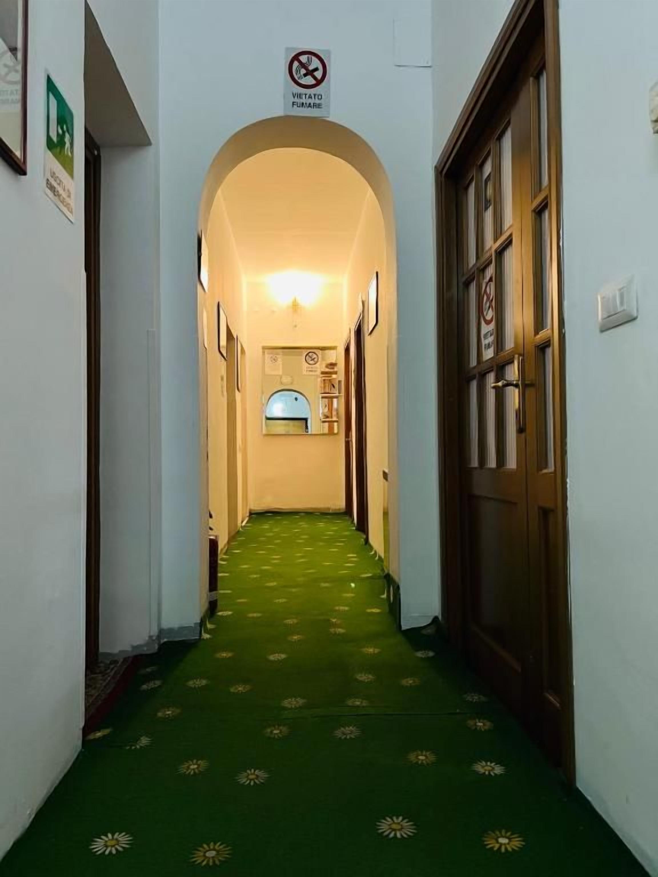 Un pasillo con alfombra verde y un cartel que indica prohibido fumar.