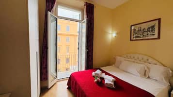 Ein Hotelzimmer mit Bett, einem Vorhangfenster, einem Bild an der Wand und Blick auf Gebäude.