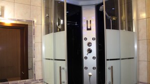 Un baño moderno con cabina de ducha de vidrio, un espejo y una puerta de madera.