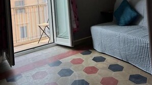 A room with a sliding glass door leading to a balcony, a bed with a blue pillow, and a patterned floor. - Affittacamere Radi (Rome)