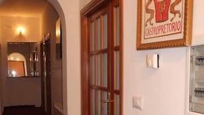 Un pasillo con puerta de madera, un emblema enmarcado en la pared y suelo alfombrado.