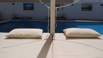 Un área junto a la piscina con dos sillas reclinables.