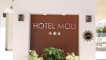 Entrada de un hotel con un letrero que dice 'HOTEL MOLÍ' y elementos decorativos.