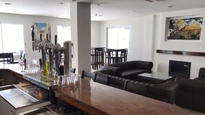 Eine moderne Bar mit Holztresen, Barhocker und einer Sitzecke mit einer Couch und Sesseln.