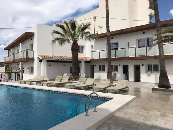 A modern hotel with a swimming pool, lounge chairs, and palm trees. - Hotel Moli Boutique (L'Alfas del Pi)