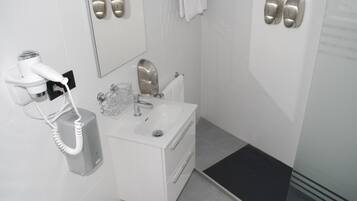 Un baño con secador de pelo, lavabo y espejo.