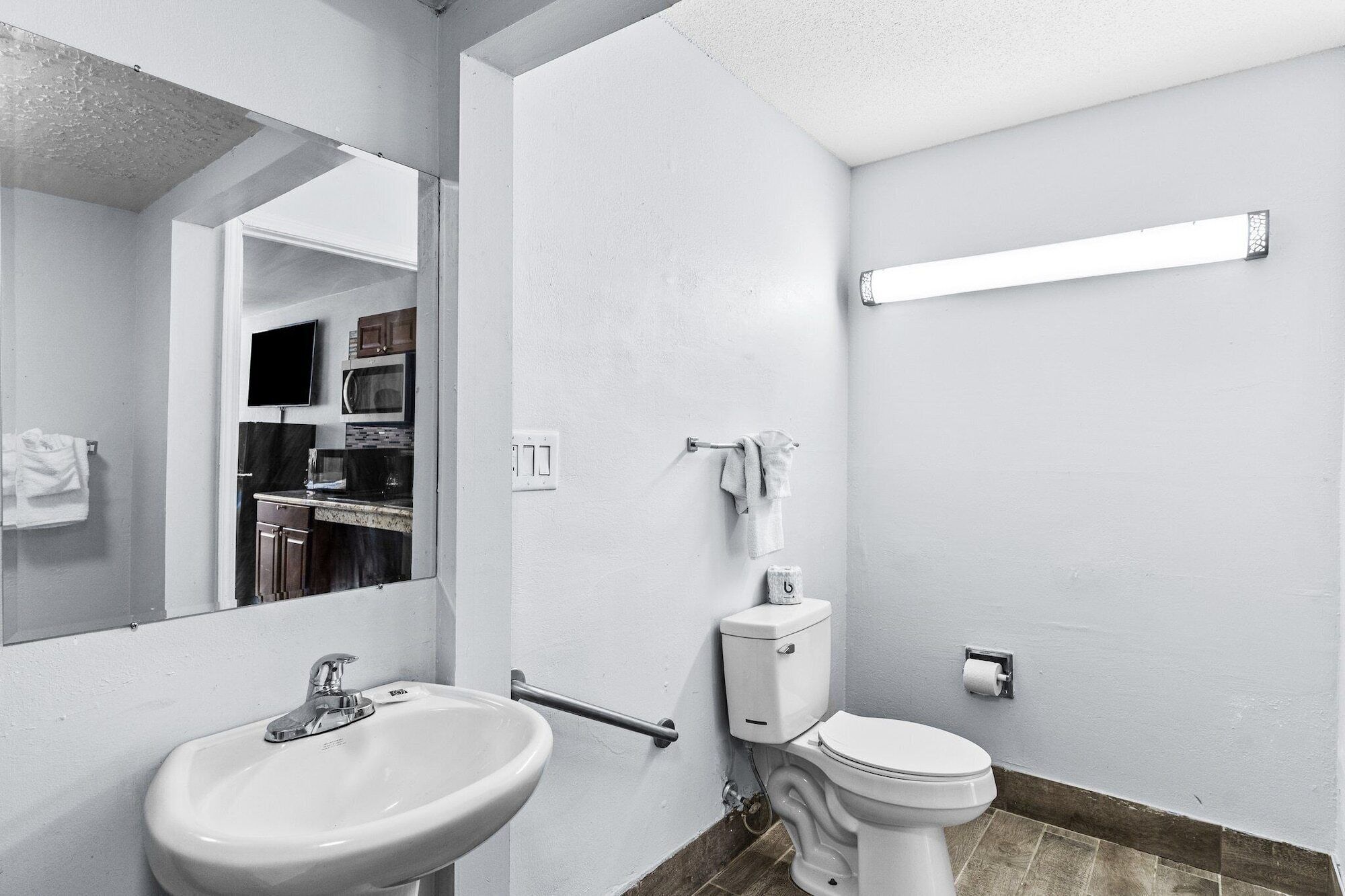 A bathroom with a white sink, toilet, and a mirror.