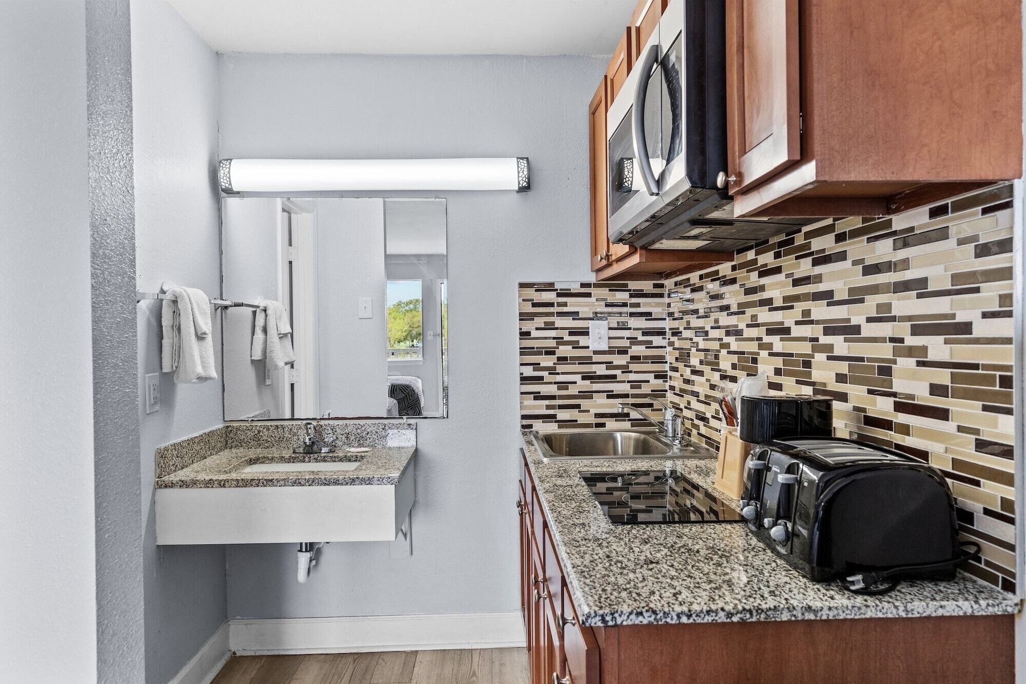 A compact kitchen with a granite countertop, a built-in microwave, and a toaster.