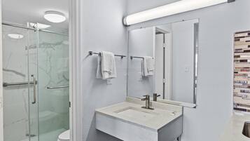 Une salle de bain avec une douche à parois de verre, un lavabo avec un miroir et un mur carrelé.