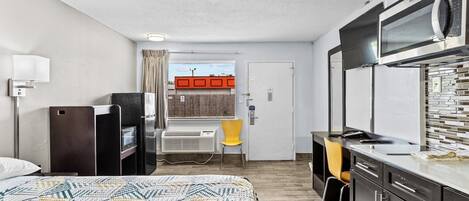 Habitación de hotel compacta con cama, kitchenette y un pequeño escritorio.
