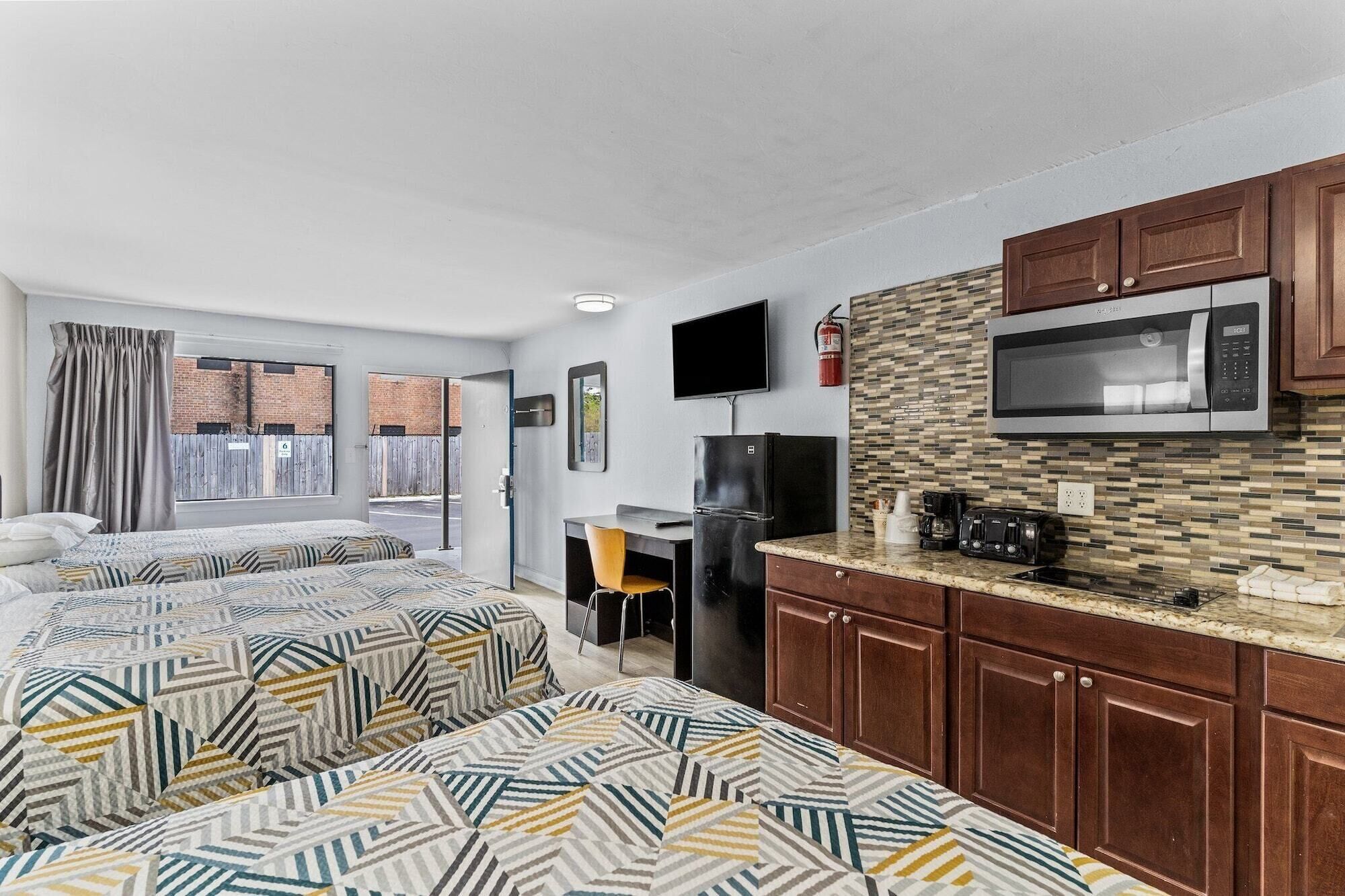 Une chambre d’hôtel avec deux lits, une kitchenette, un téléviseur à écran plat et un extincteur.