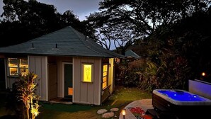 Uma casa com hidromassagem, um pequeno alpendre e um cachorro no quintal.