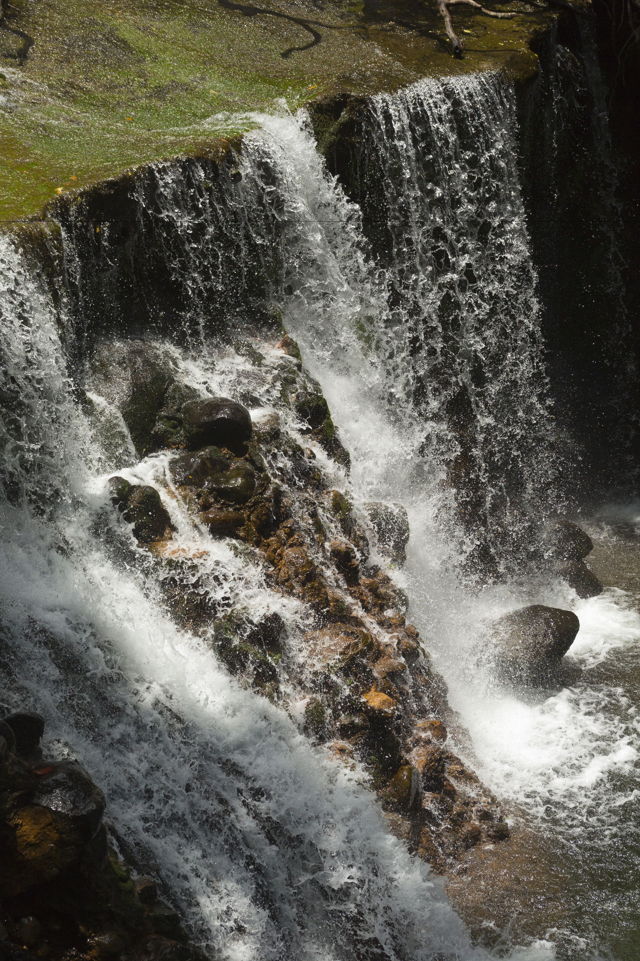 A waterfall cascading over rocks with a mossy ledge above.