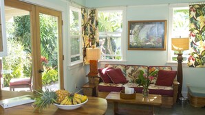 Uma sala de estar acolhedora com uma mesa de centro de madeira, um sofá com almofadas florais e um quadro na parede.