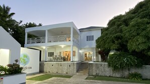 A modern two-story house with a swimming pool and a covered patio area. - All Nations Guesthouse (Port Antonio)