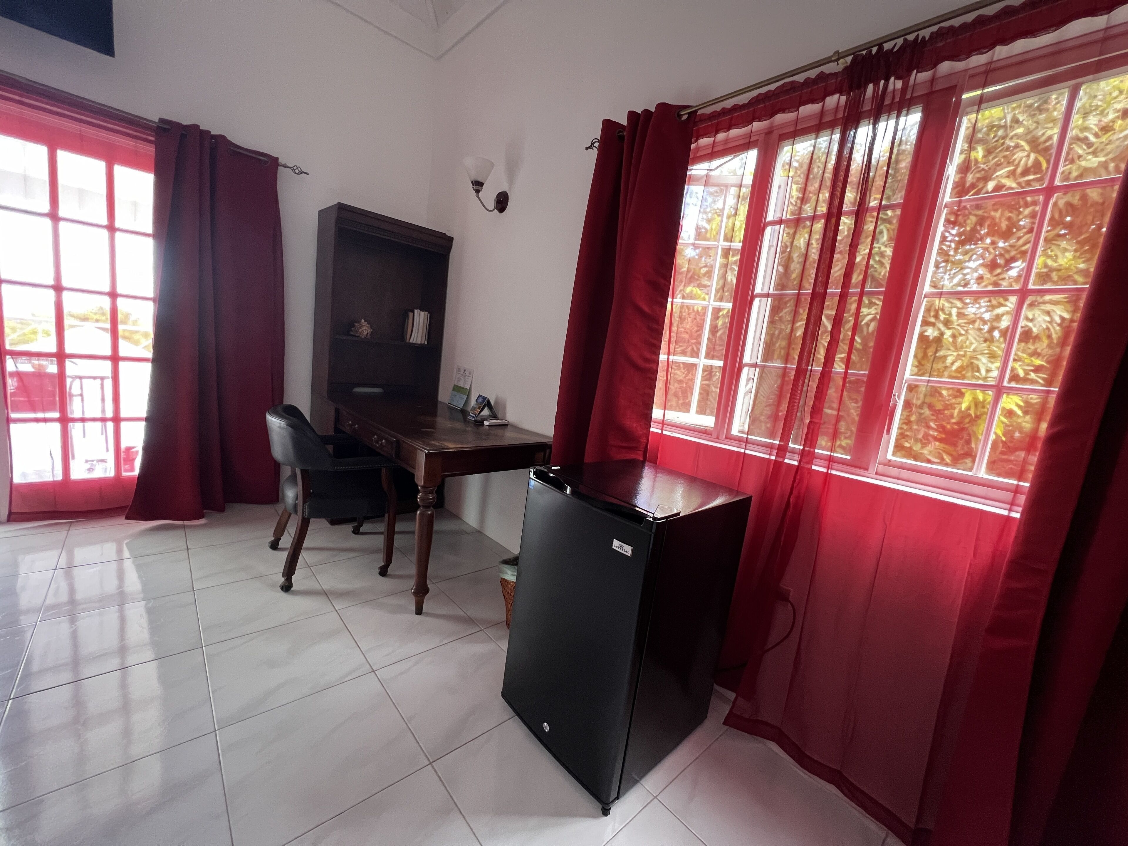 Une chambre équipée d’un bureau, d’une chaise et d’un petit réfrigérateur.