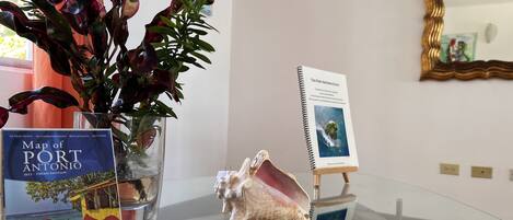 A glass table with a map of Port Antonio, a decorative shell, and a guidebook on a stand.