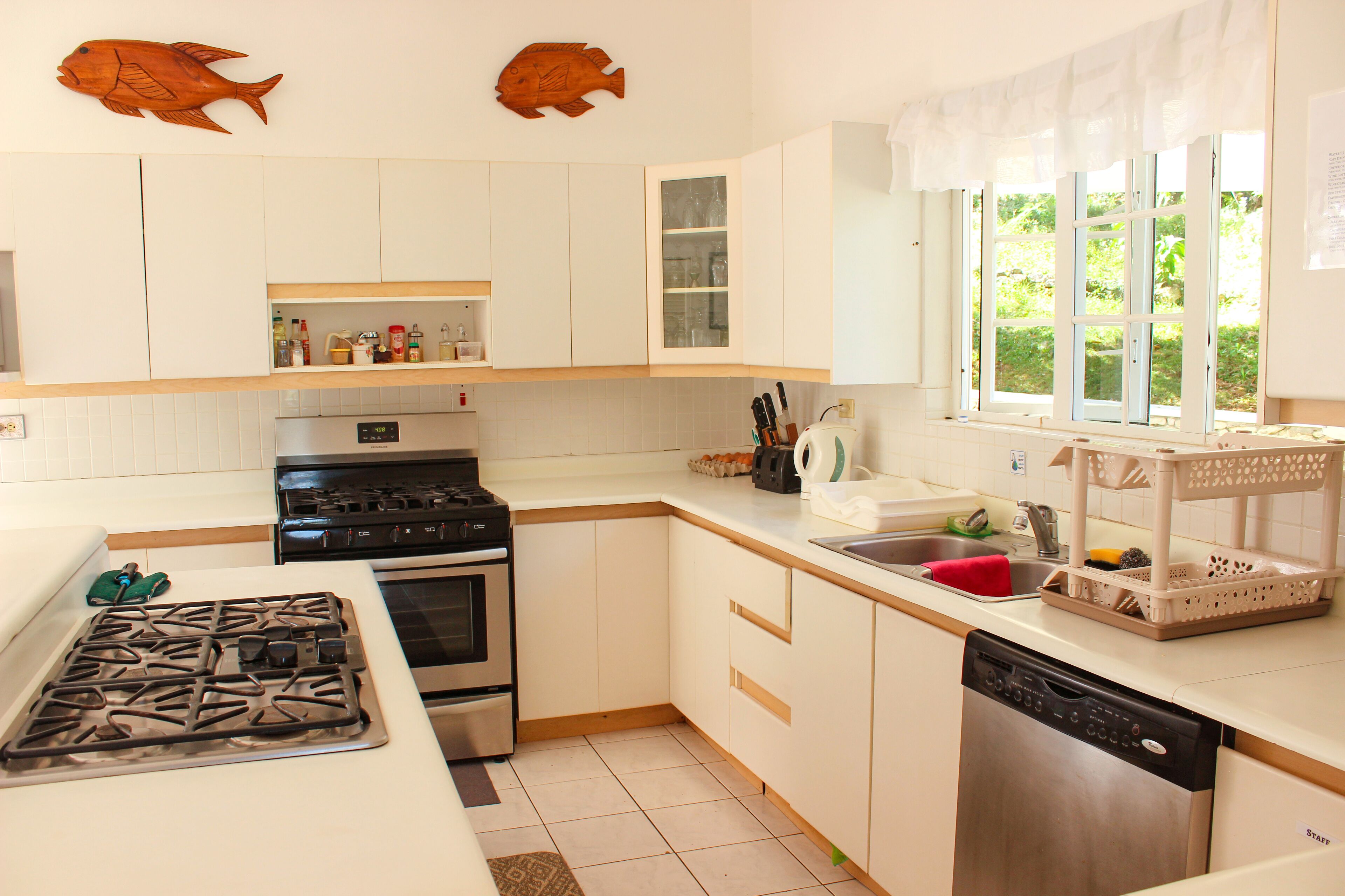 A modern kitchen with white cabinets, a stainless steel stove, and a dishwasher.