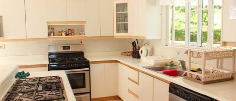 A modern kitchen with white cabinets, a stainless steel stove, and a dishwasher.