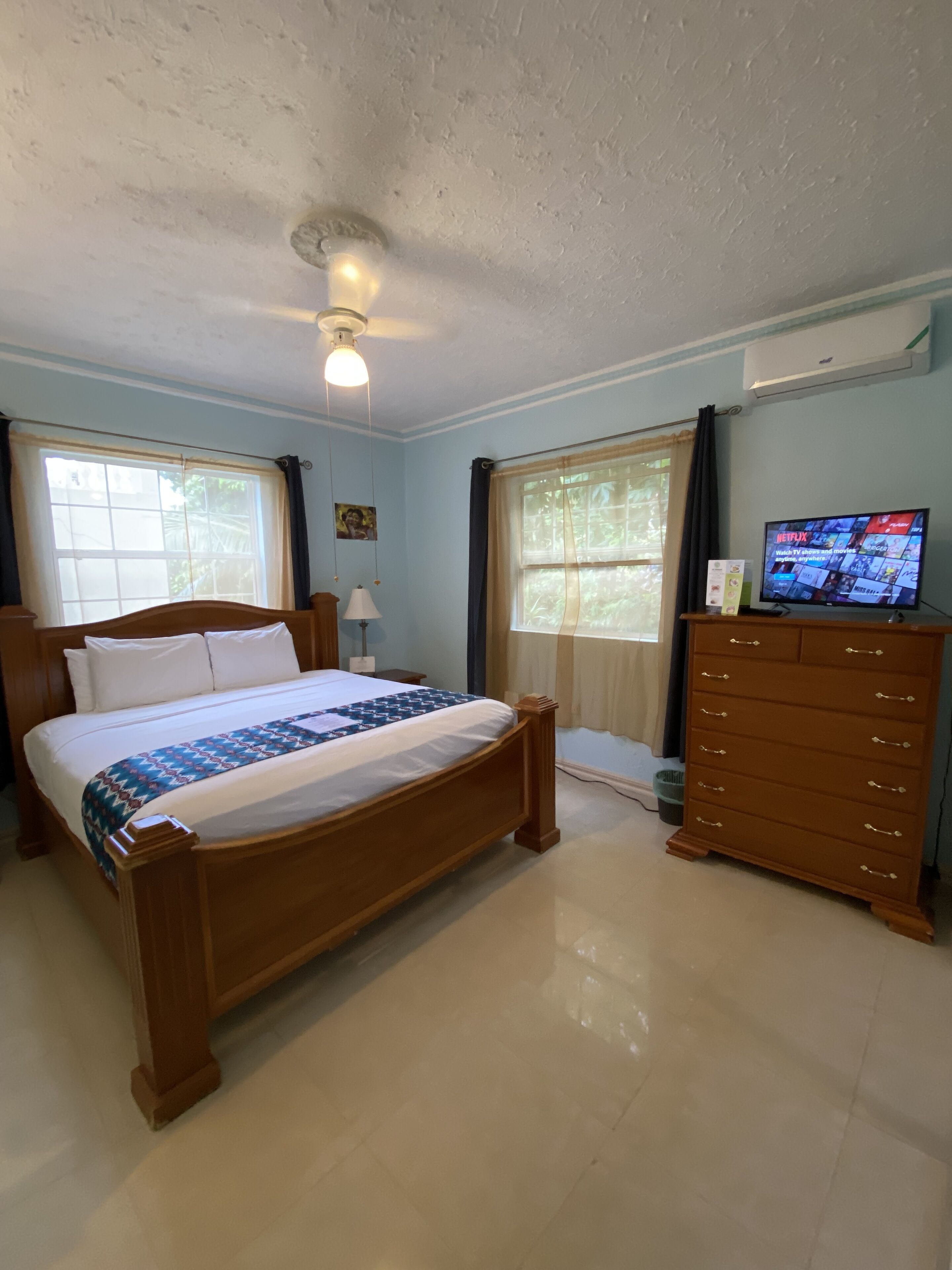 Un dormitorio con una cama de madera, un aparador y un televisor que muestra Netflix.