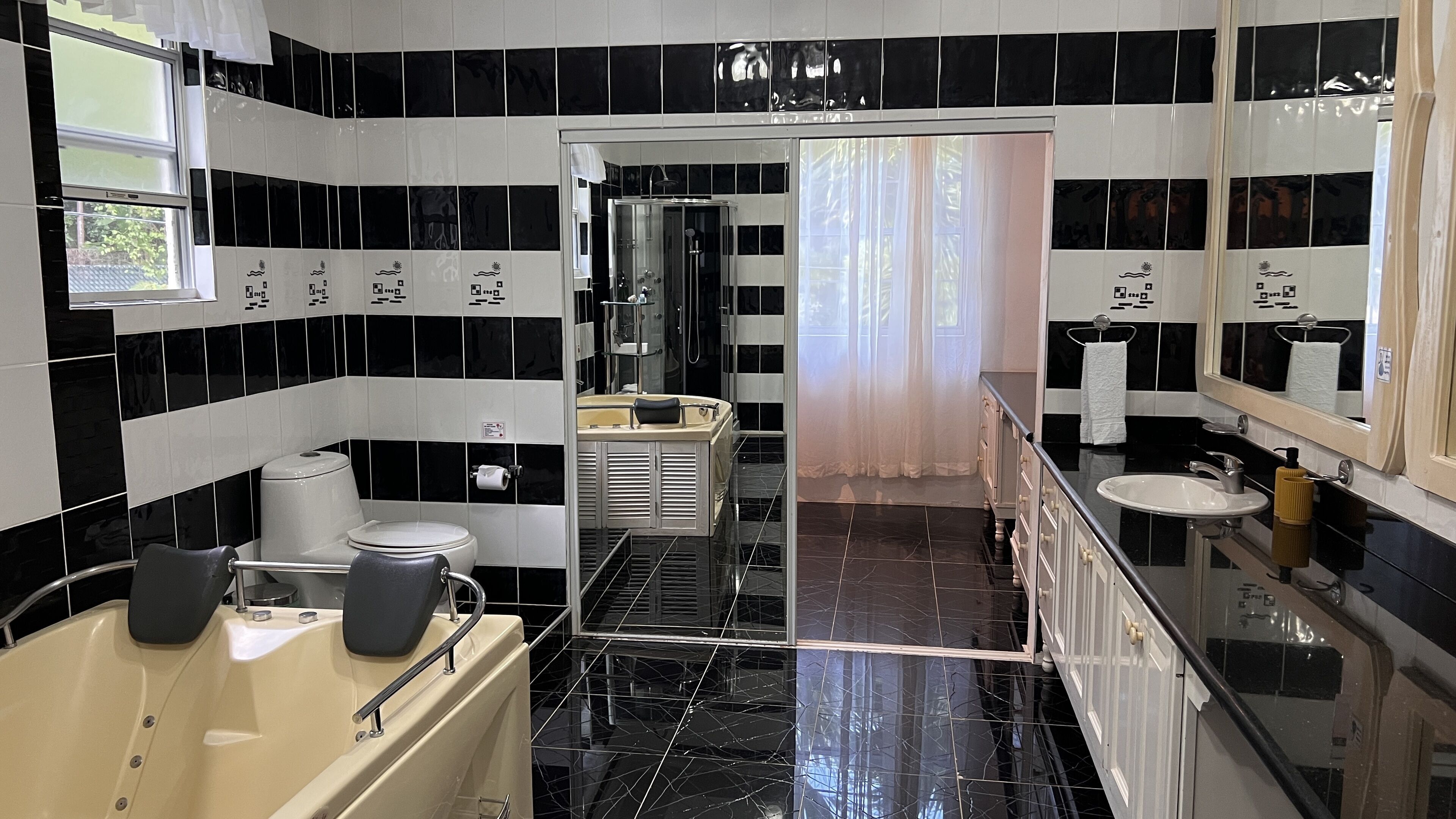 A modern bathroom with black and white tiles, a bathtub, a toilet, and a sink.
