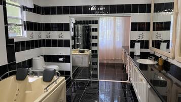 A modern bathroom with black and white tiles, a bathtub, a toilet, and a sink.