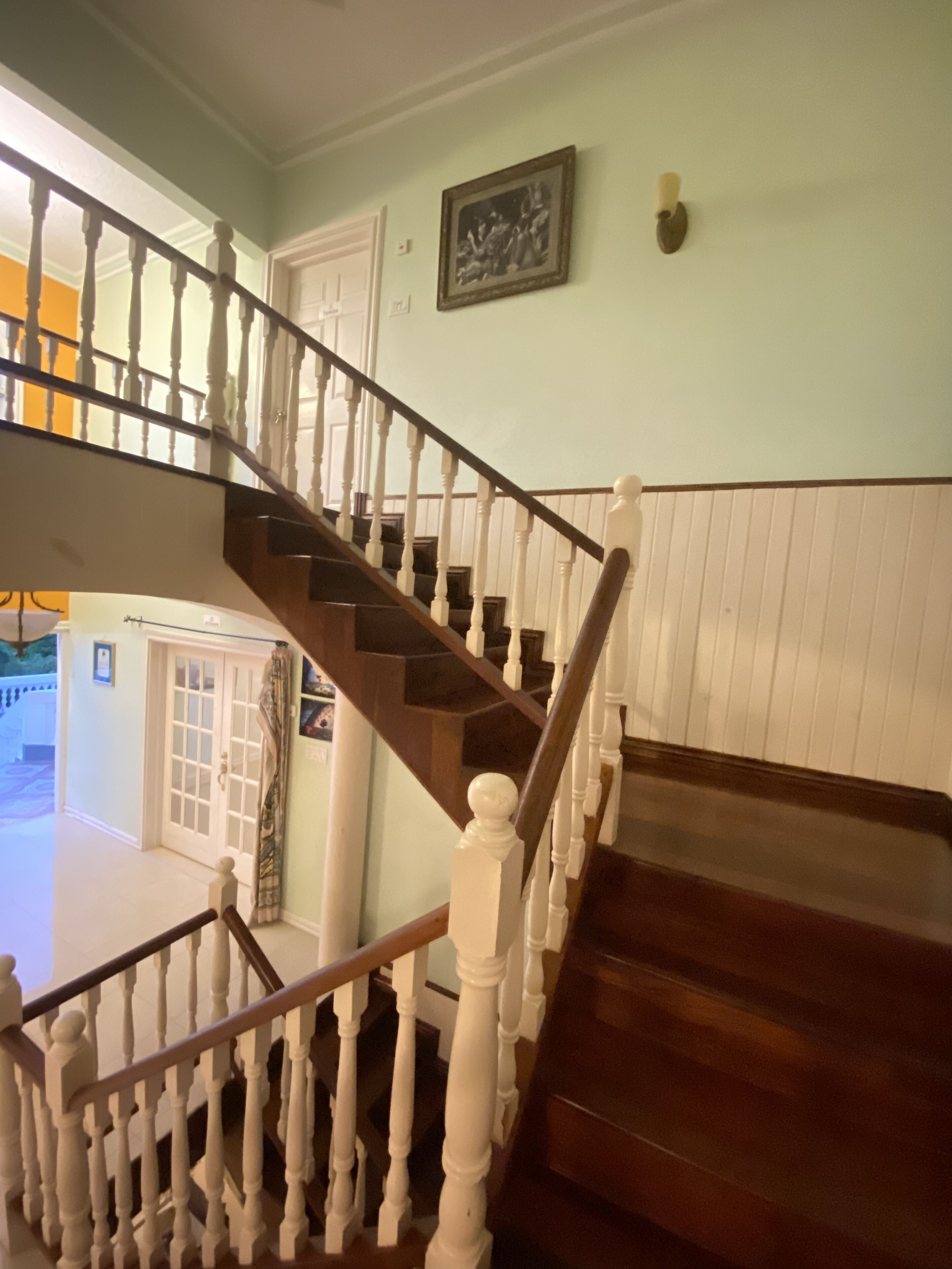 A wooden staircase with white balusters and a dark wooden handrail leading to an upper floor.