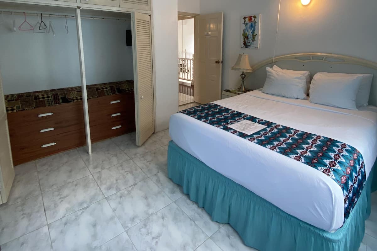 A bedroom with a bed, a wardrobe, a fan, and a wall-mounted light.