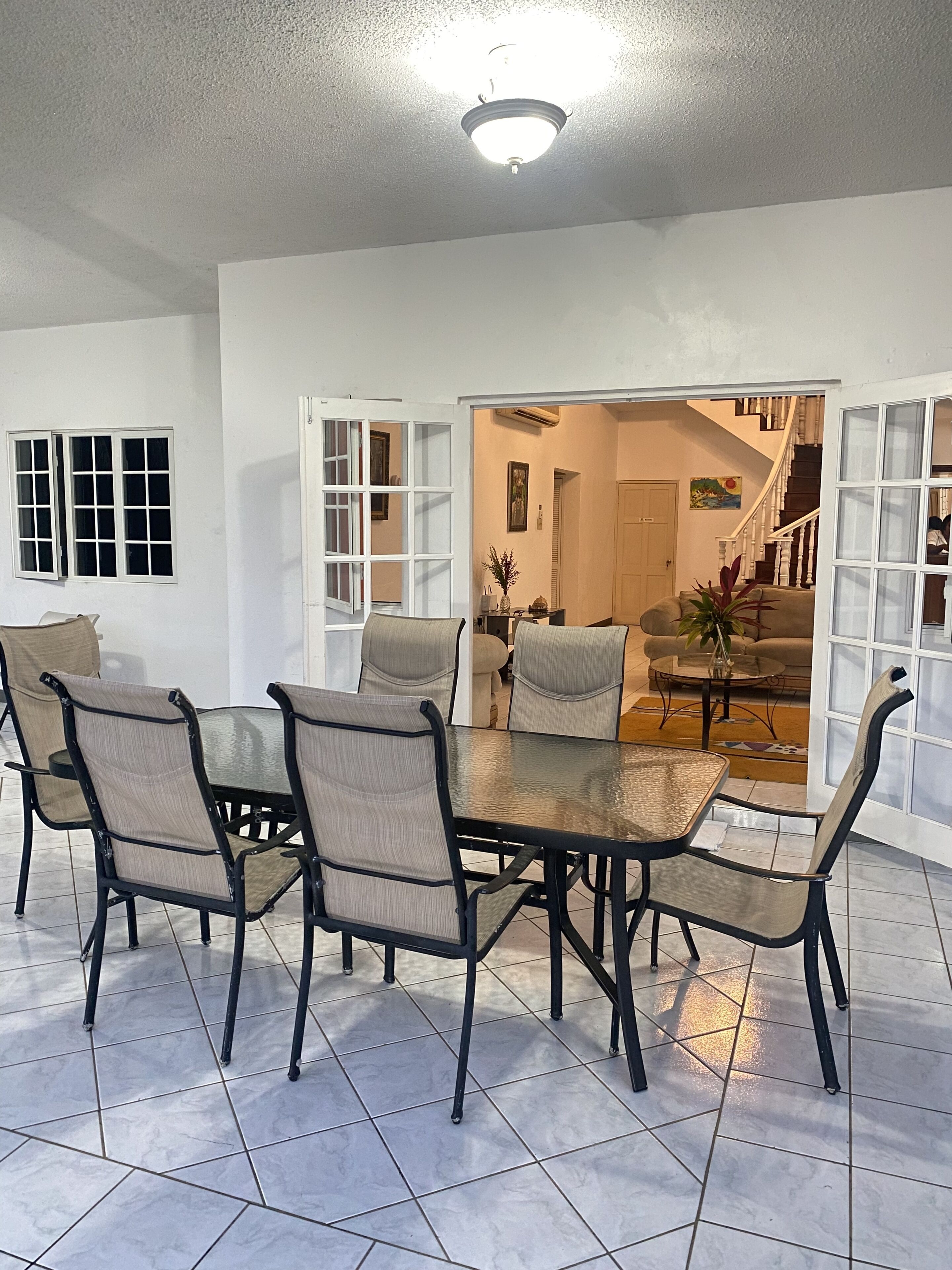Un espace repas comprenant une table et des chaises, un luminaire au plafond et une vue sur un escalier menant à une autre pièce.