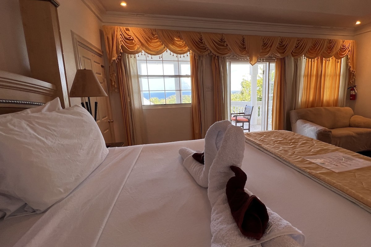 A hotel room with a large bed, a sofa, and a view of the outdoors.