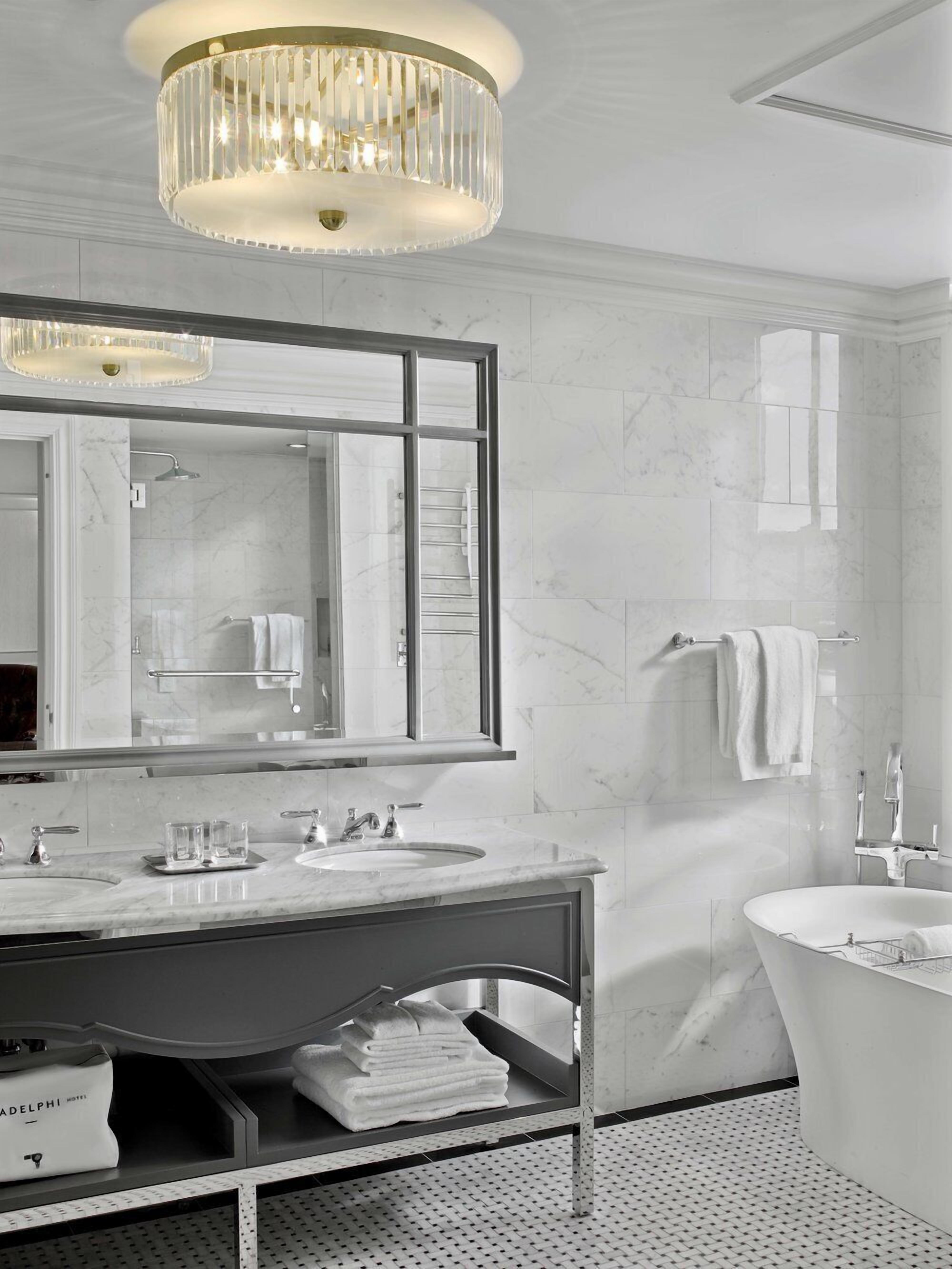 Une salle de bain moderne avec un grand miroir, un meuble-lavabo et une baignoire sur pieds.
