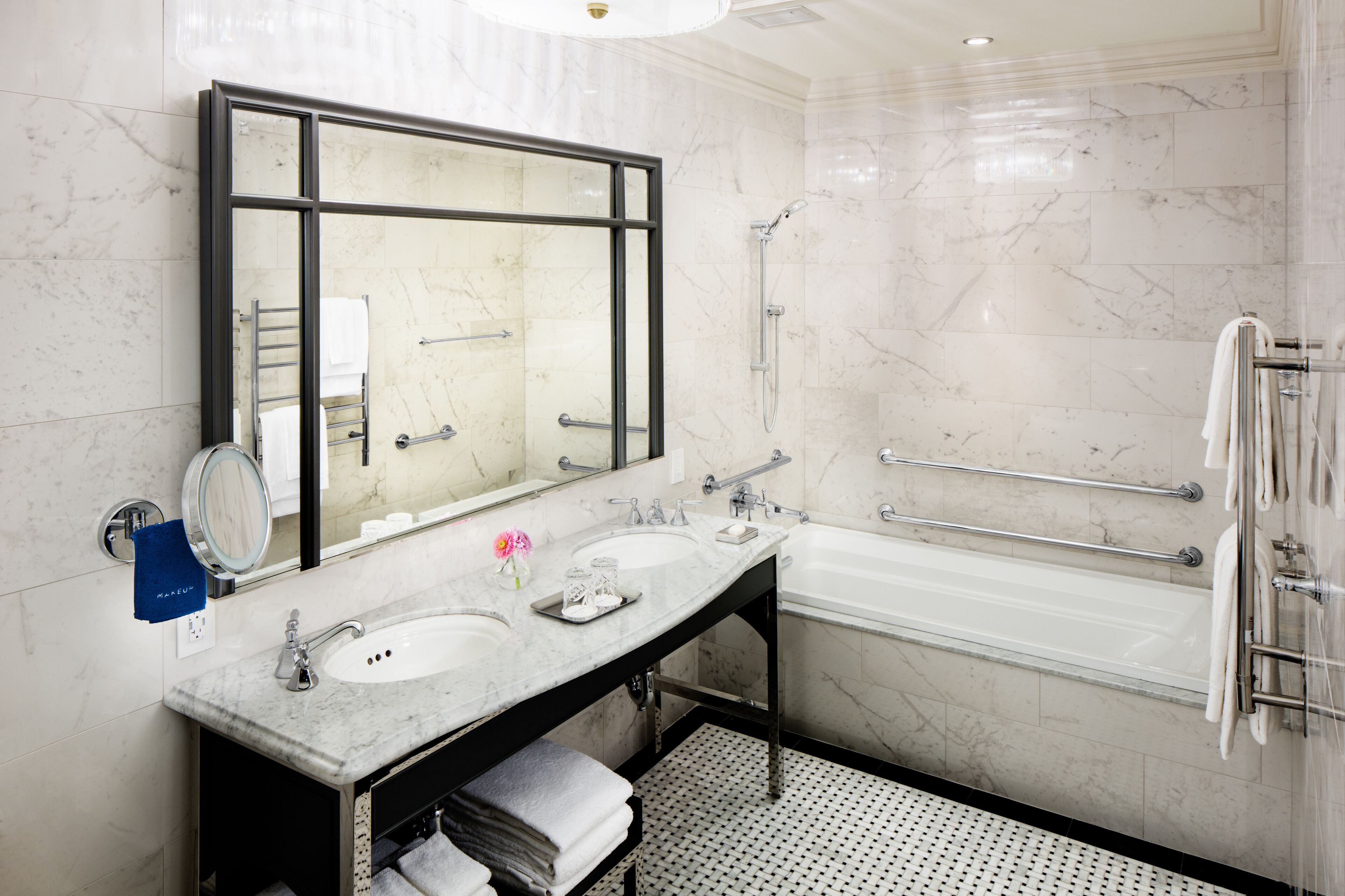 A modern bathroom with a large mirror, two sinks, a bathtub, and a shower.