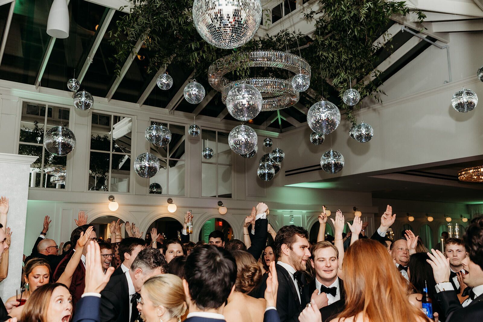 Eine gut besuchte Indoor-Veranstaltung mit Discokugeln und jubelnden Menschen.