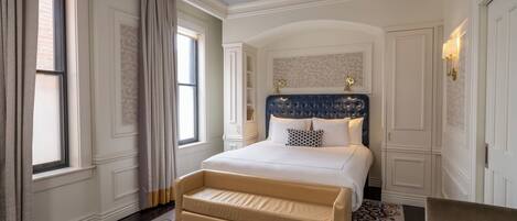 Un dormitorio con una cama grande, un banco, una ventana y una puerta.