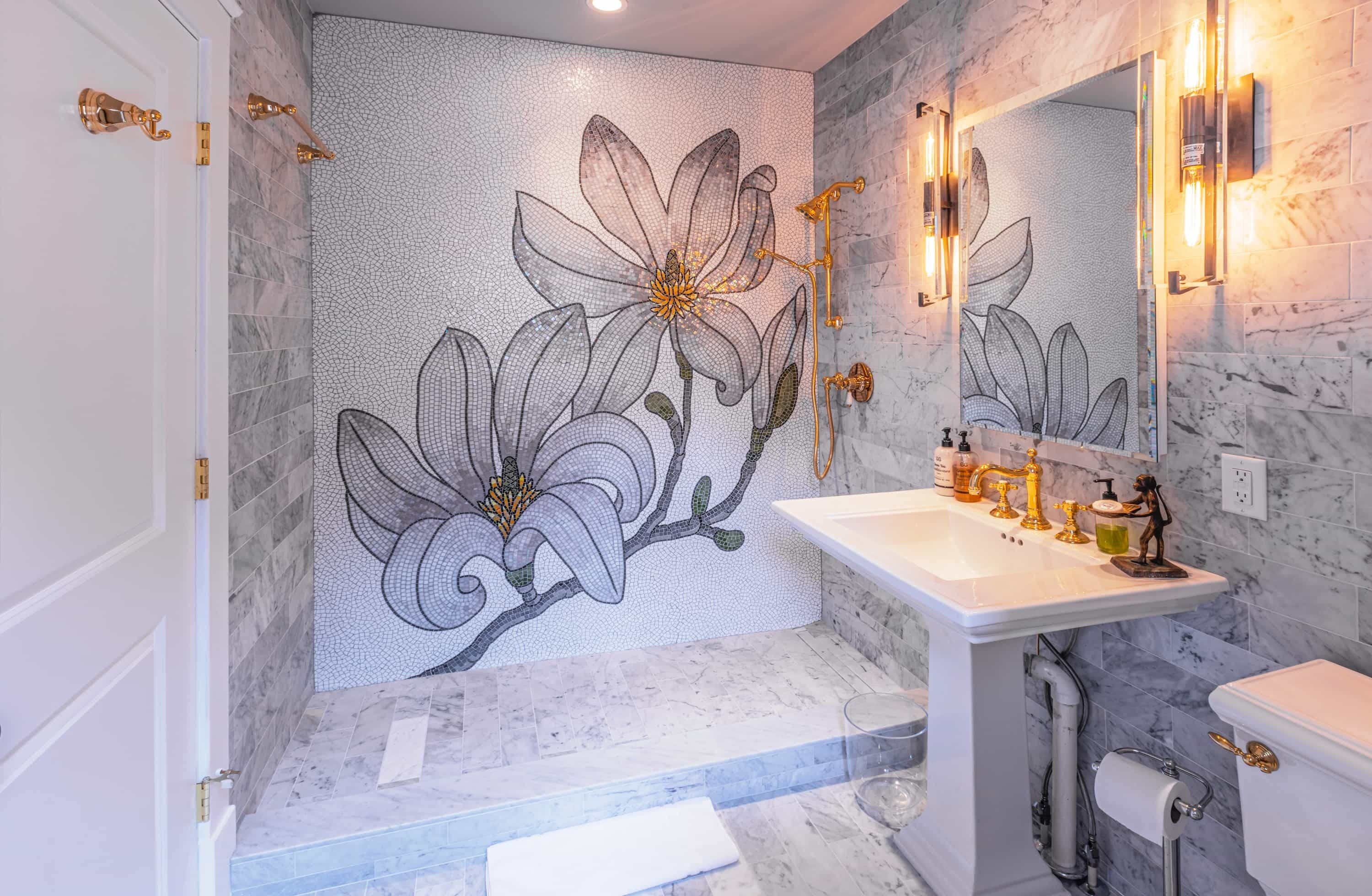 Un baño con pared de mosaicos, un lavamanos blanco y un inodoro.