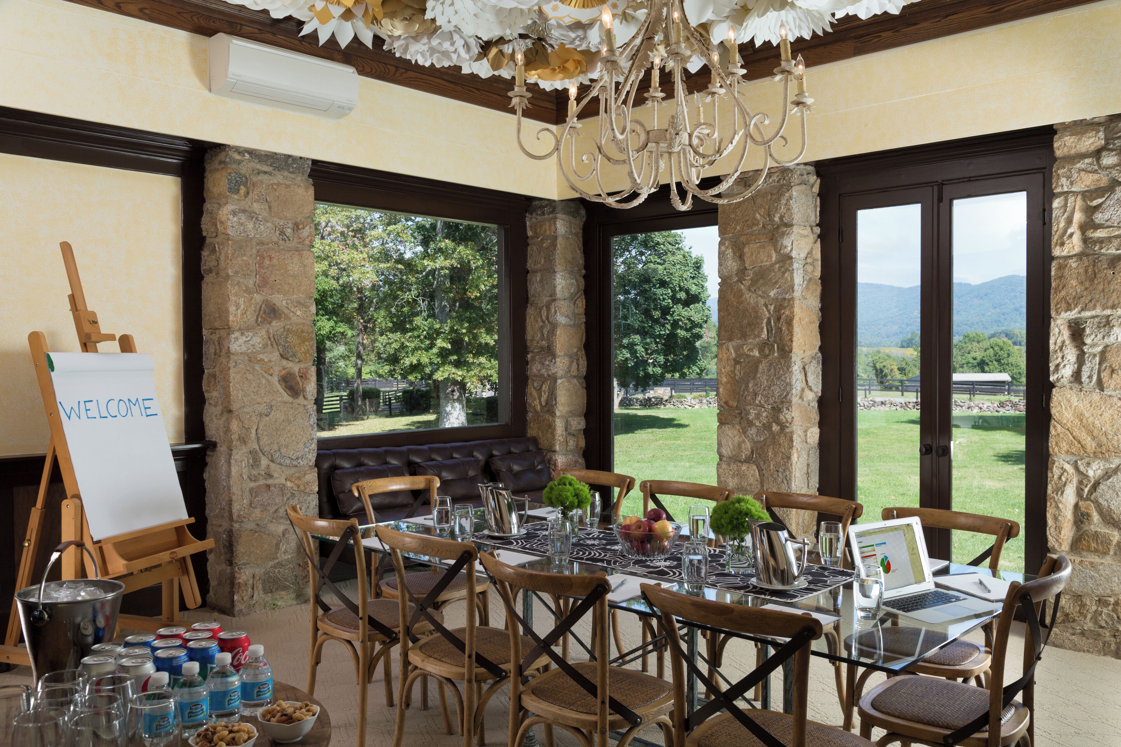 Zona pranzo con pareti in pietra, un lampadario e un portatile sul tavolo.