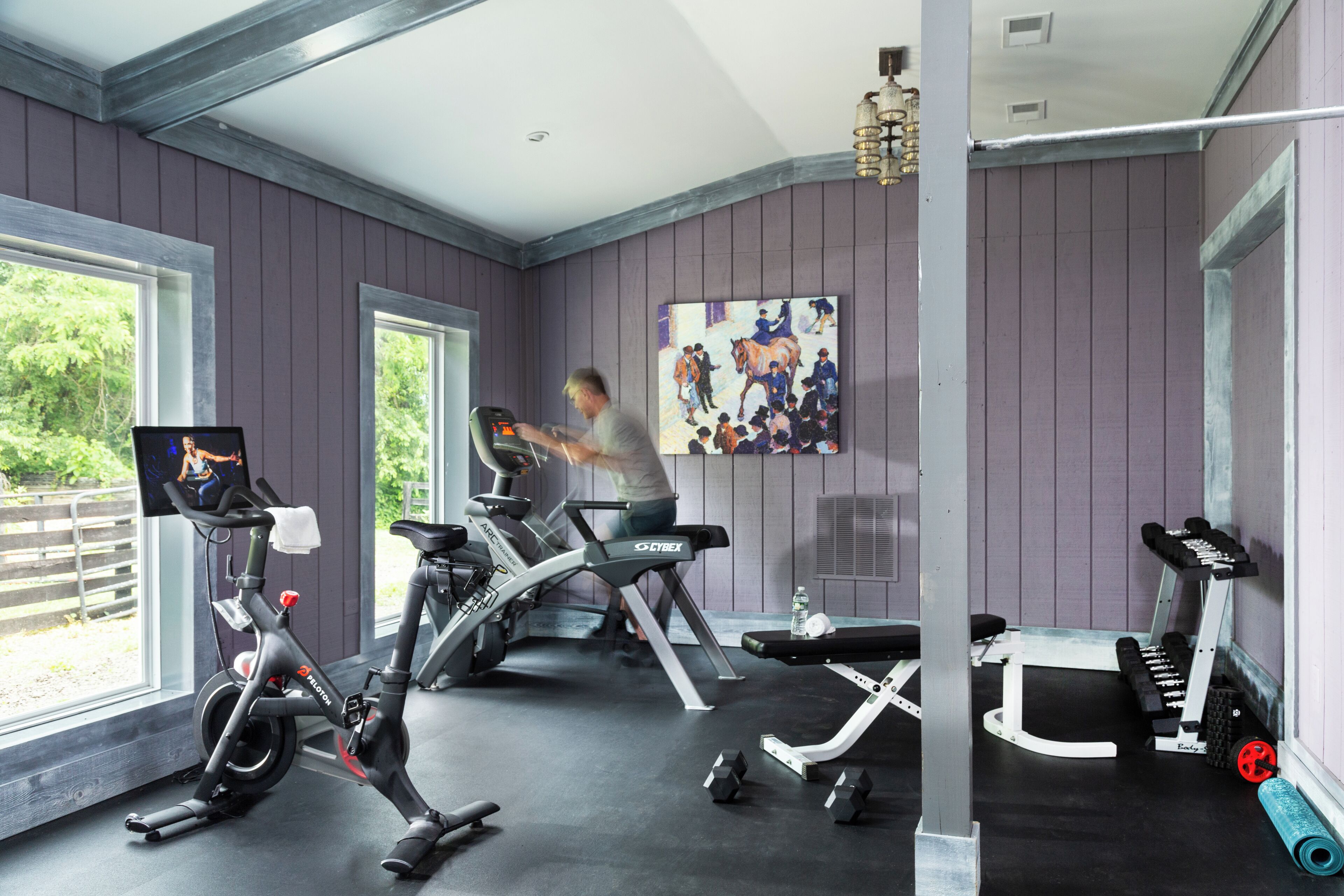 Un gimnasio en casa con equipo de ejercicio, que incluye una bicicleta estática, una cinta de correr y un banco de pesas.