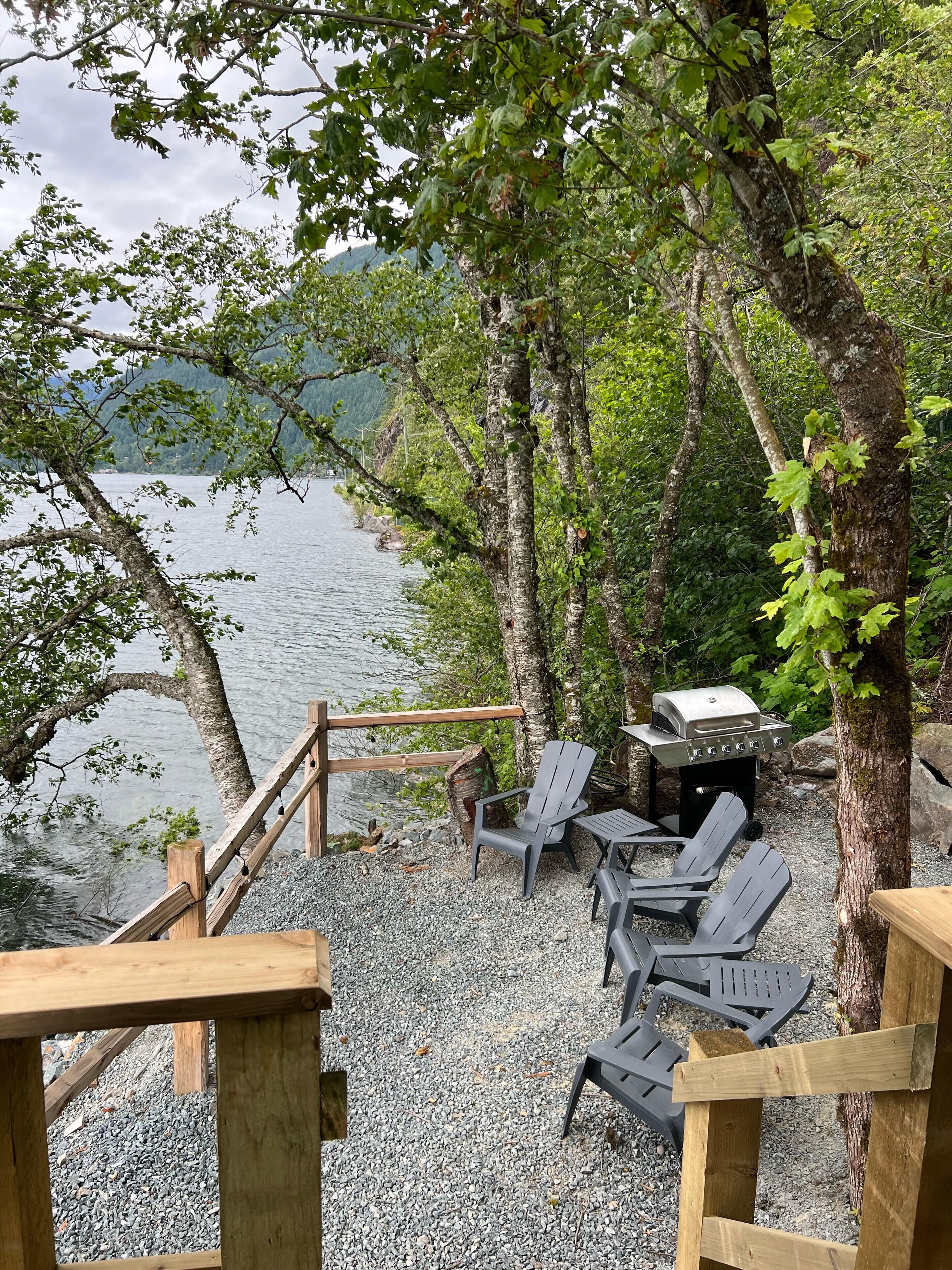 Eine Terrasse mit Sitzgelegenheiten und Grill mit Blick auf einen See.