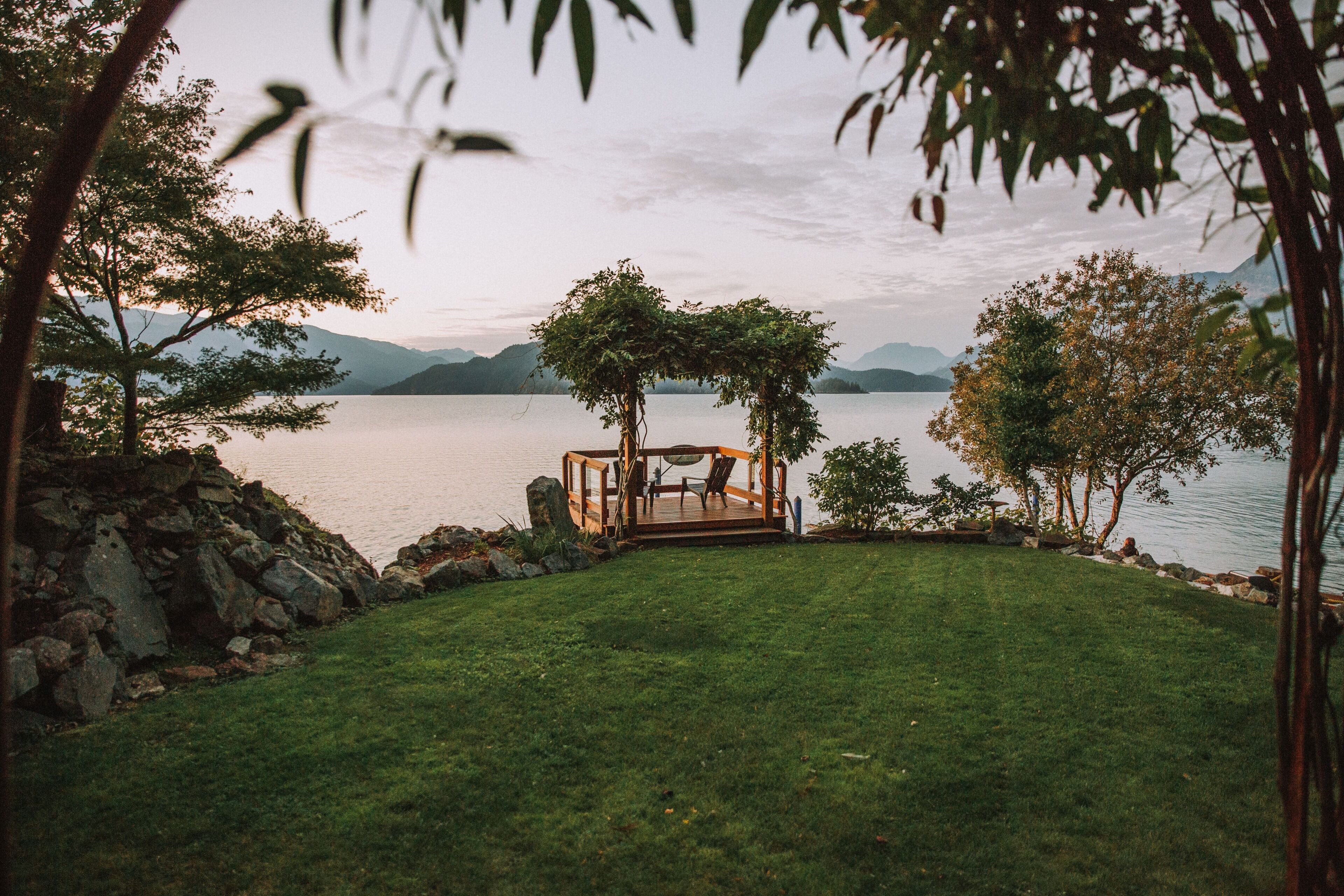 Um gazebo com vista para um lago e montanhas ao fundo.
