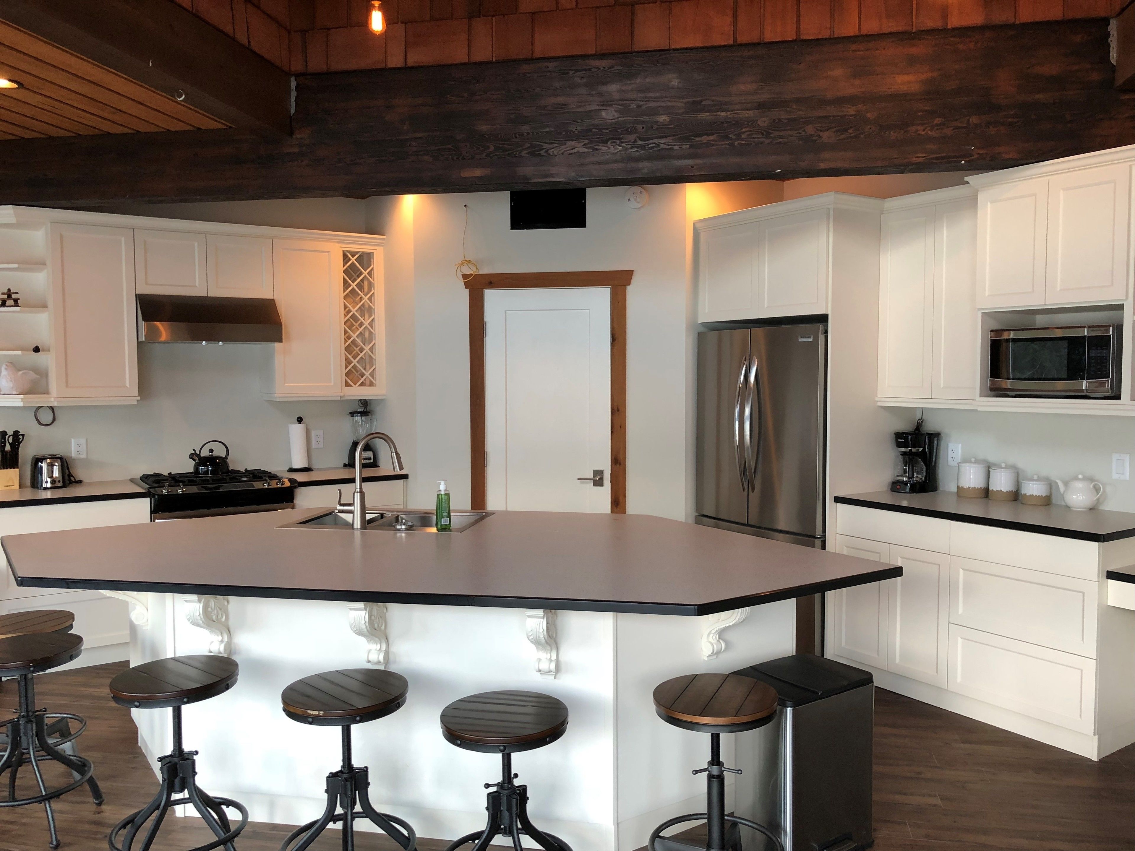 A modern kitchen with a large island, stainless steel appliances, and bar stools.
