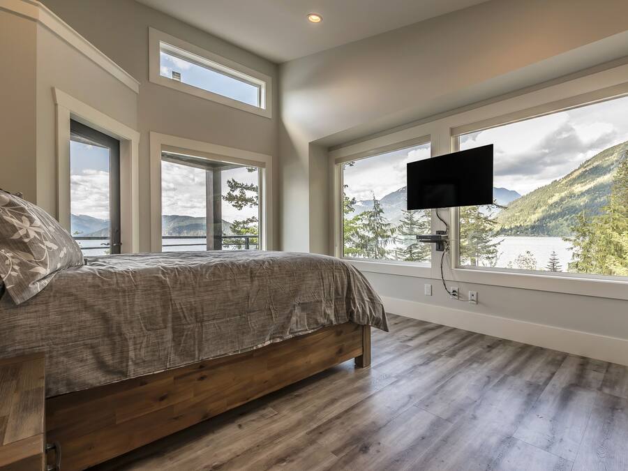 Een slaapkamer met een groot bed, houten vloeren en een aan de muur bevestigde televisie.