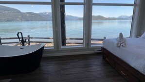 Un dormitorio con un ventanal grande, una bañera y una cama con una toalla.