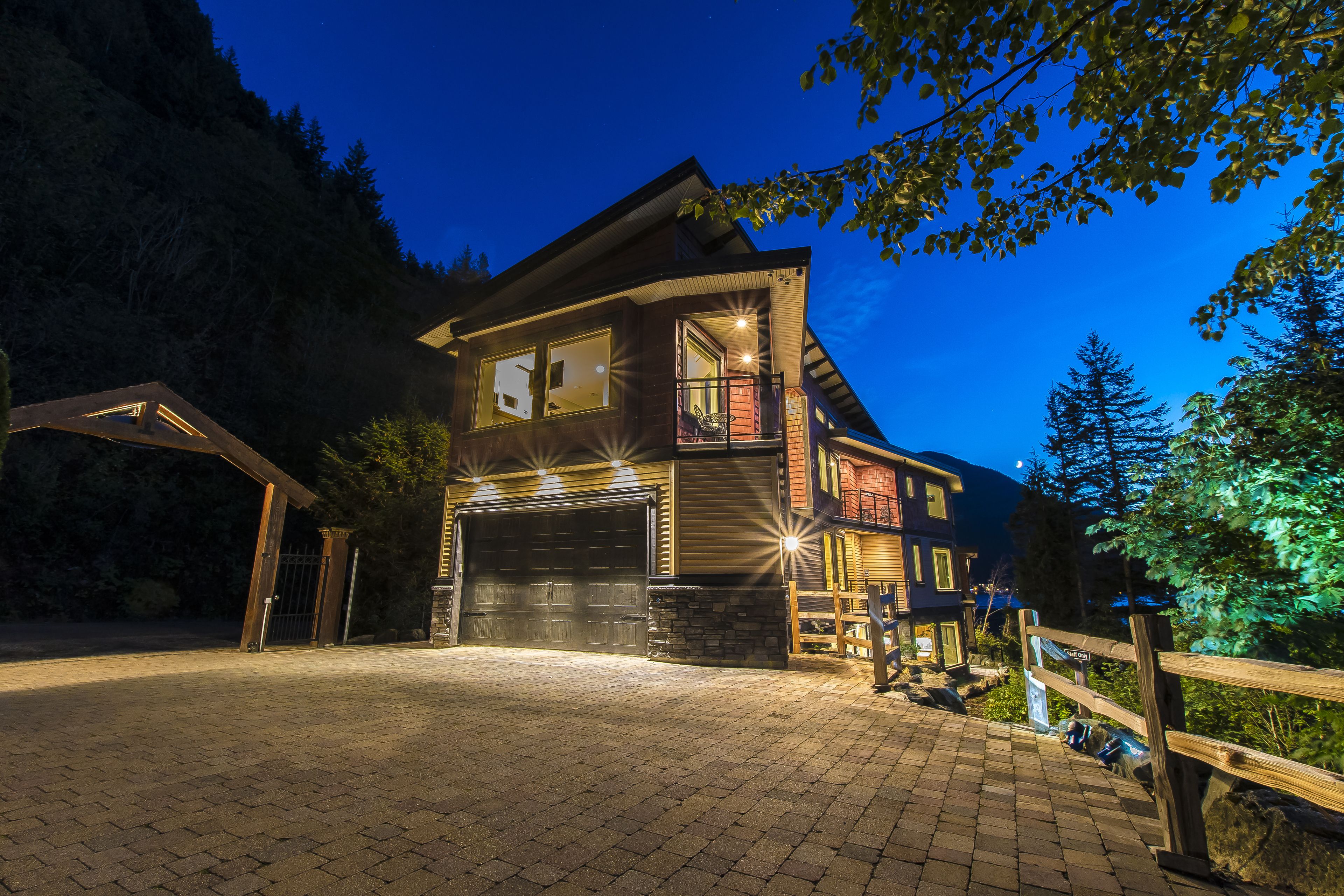 A two-story house with a garage, a covered driveway, and a wooden fence.