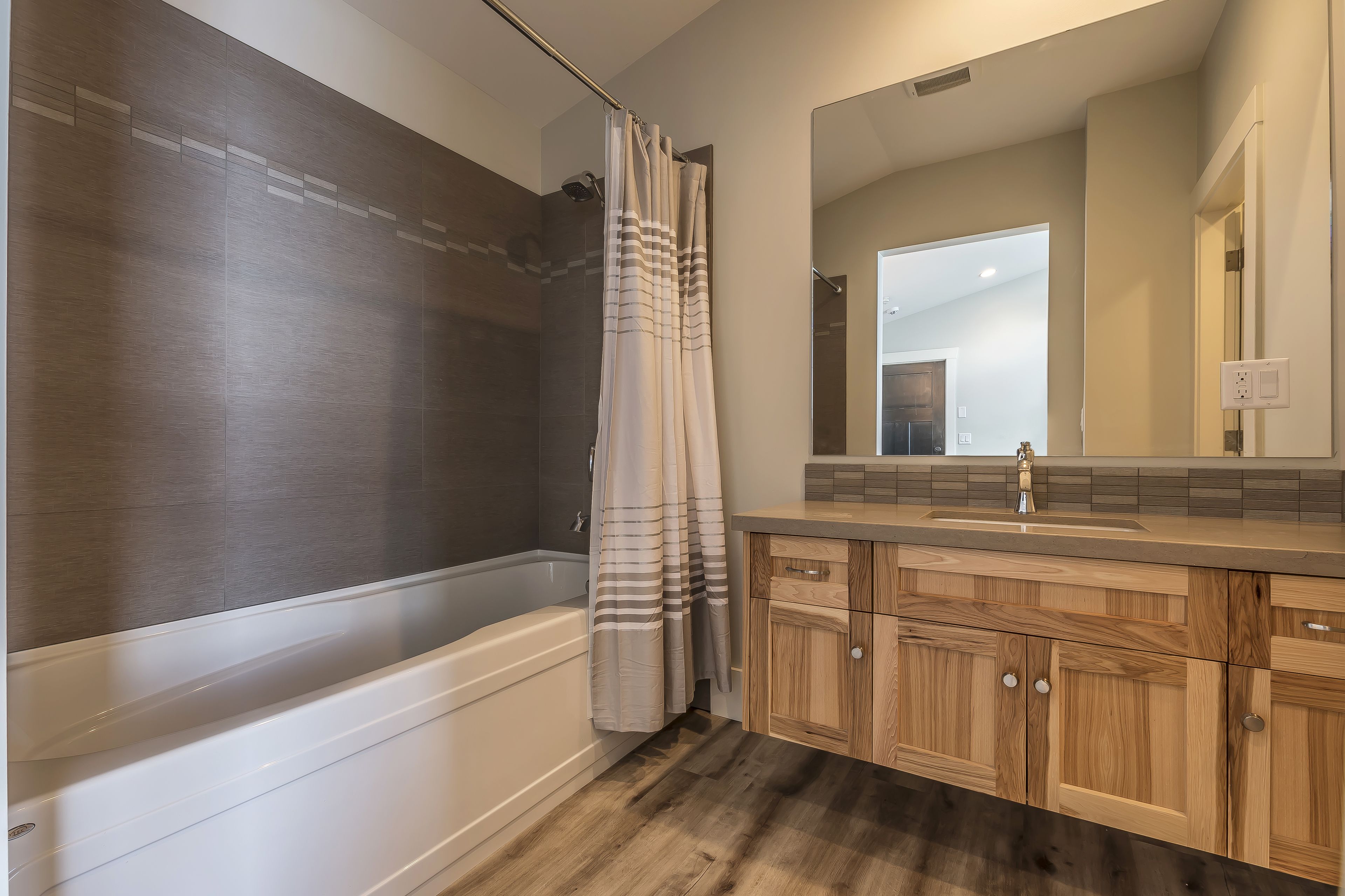 Un baño moderno con bañera, tocador de madera y un espejo grande.