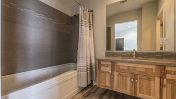 Un baño moderno con bañera, tocador de madera y un espejo grande.