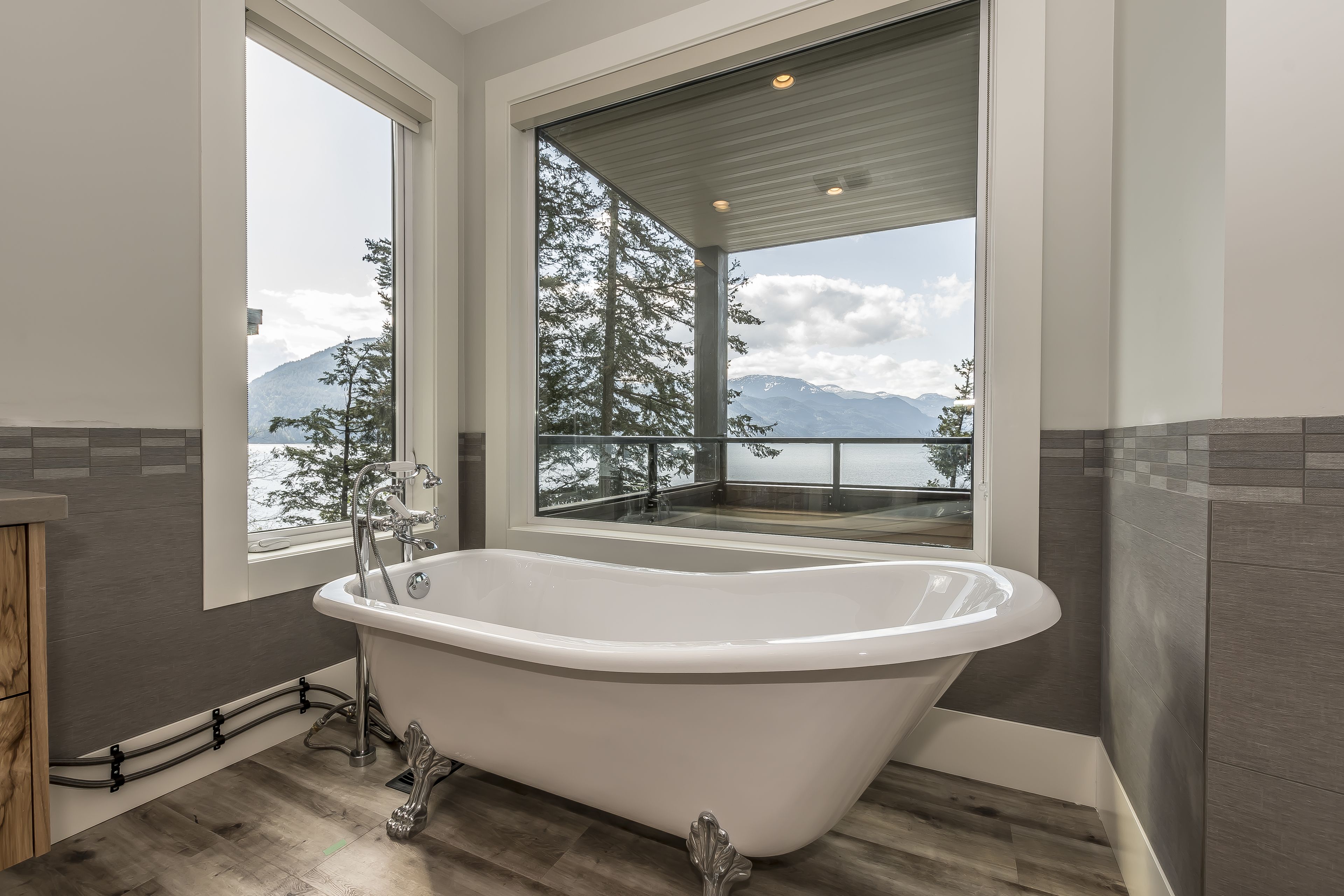 A modern bathroom with a freestanding bathtub, large windows, and a view of mountains.