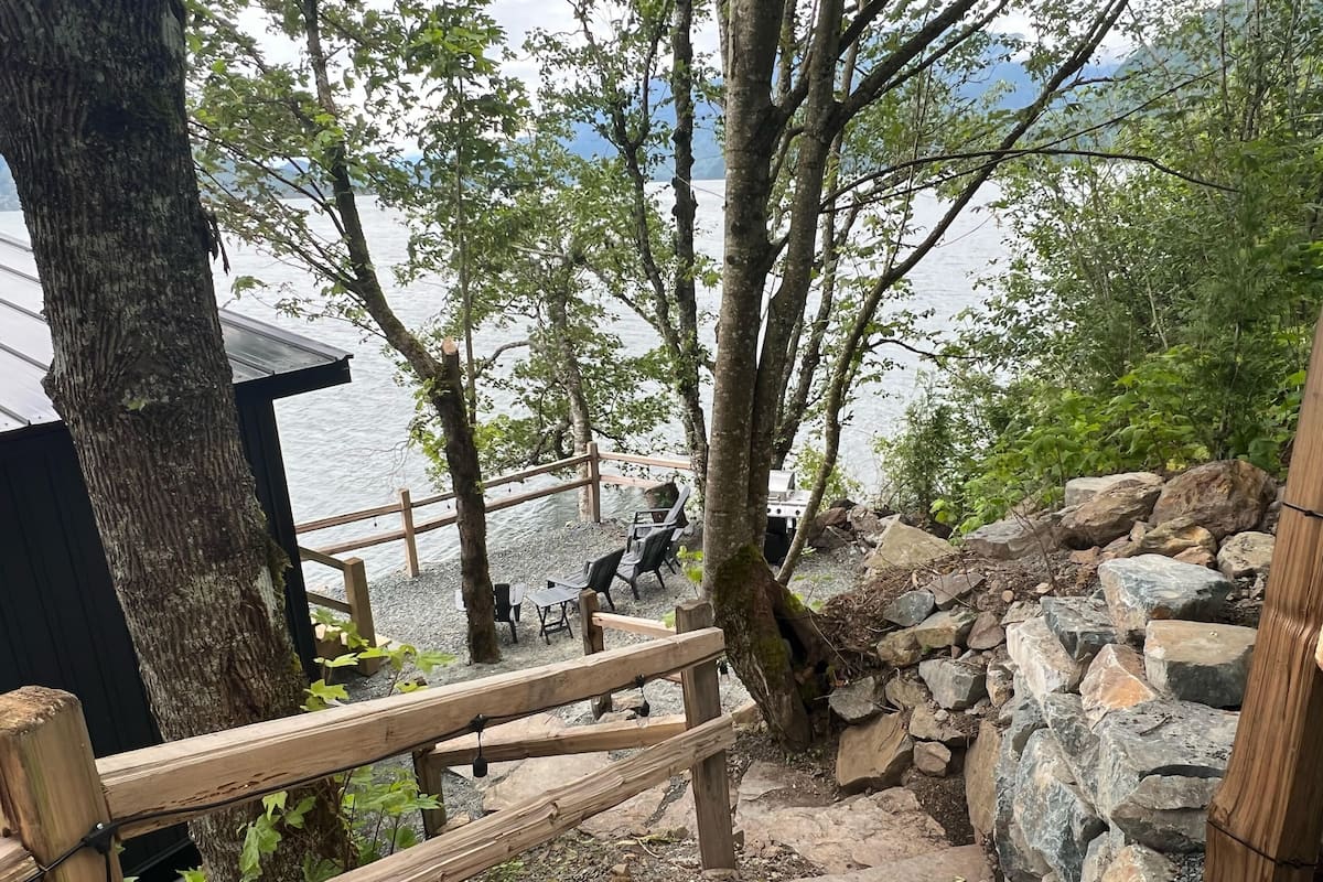 Eine Holzterrasse mit Blick auf einen See, umgeben von Bäumen und Felsen.