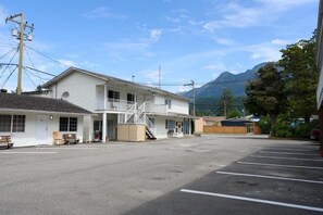 A two-story motel with a covered front porch, a staircase leading to the second floor, and a parking lot in front. - Park Motel (Hope)