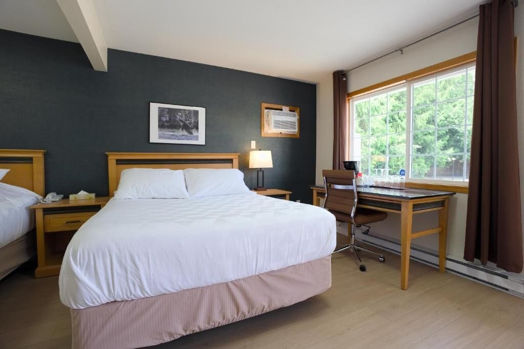 A hotel room with a large bed, a desk, and a window with curtains.